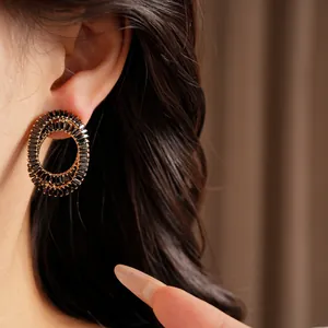 Close-up macro view of luxury black zircon oval crossover stud earrings on ear