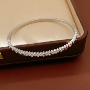 Close-up of a silver stainless steel bangle with inlaid zircons on a luxury jewelry box.