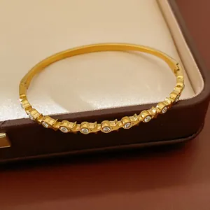 Detailed view of a gold stainless steel bangle inlaid with sparkling cubic zirconia