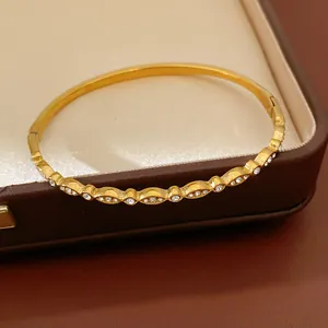 Macro detail shot of a gold stainless steel bangle bracelet with sparkling zircon accents