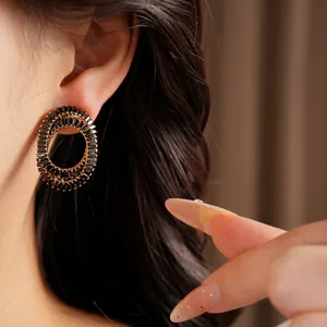 Close-up of elegant oval gold earrings with black zircon stones on model