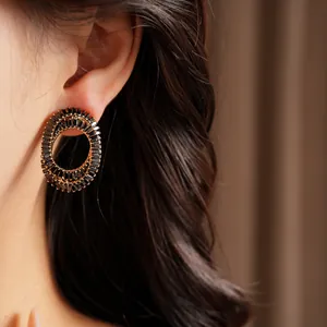 Detailed macro shot of elegant oval earrings with black zirconia set on a model's ear