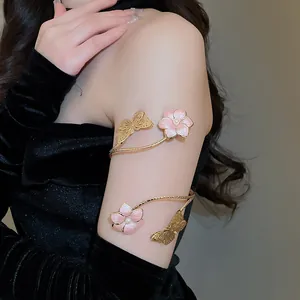 Detail van elegante gouden vlinder en roze bloem armband op de bovenarm