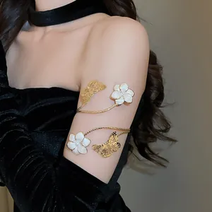 Elegante gouden vlinder en witte bloemen bovenarmband sieraad op de arm van het model.