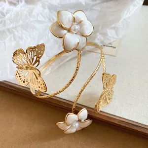Detailopname van een elegante gouden armmanchet met emaille bloemen en vlinderdetails