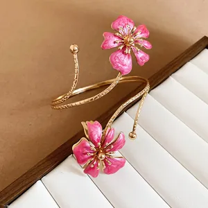 Gedetailleerd overzicht van een elegante roze emaille bloemarmband met goudkleurige spiraalband