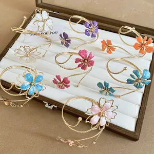 Detailopname van diverse kleurrijke emaille bloemenarmbanden in een houten doos
