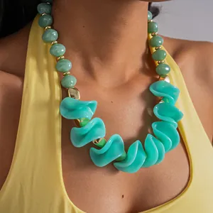 Gros plan de grosses perles en acrylique sarcelle et perles vertes marbrées sur un collier.