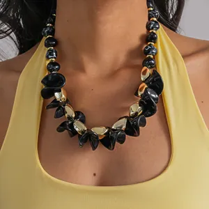 Gros plan d'un collier en perles d'acrylique géométriques noires et dorées