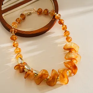 Détail du collier en perles acryliques géométriques ambre avec accents dorés.