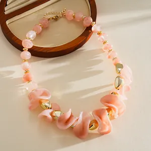 Gros plan de perles en acrylique rose marbré et de touches dorées sur un collier