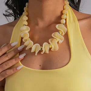 Gros plan d'un collier de perles géométriques irrégulières en acrylique jaune épais
