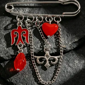 Detalle de broche de estilo étnico kazajo con dijes de corazón rojo y pájaro en piedra.