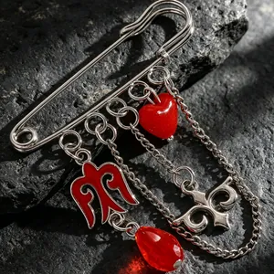 Detalle de un broche de estilo kazajo en tono plateado con dijes de esmalte rojo sobre roca