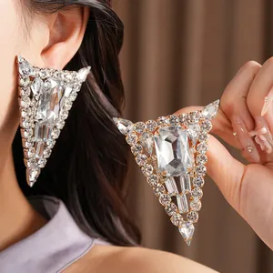Detailed view of oversized triangular sparkling rhinestone statement earrings shown on a model