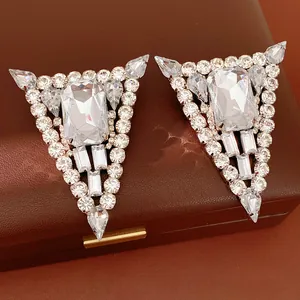 Macro view of luxurious triangle earrings with clear rhinestones on a leather box.