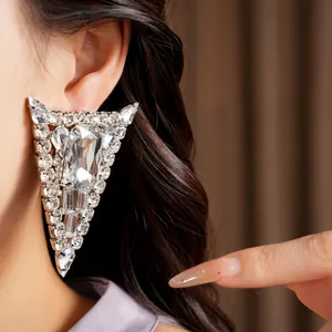 Close-up of oversized silver triangle statement earrings with sparkling crystals