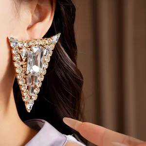 Exquisite close-up showing the detail of oversized triangular earrings with sparkling crystals