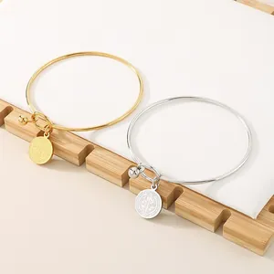 Pair of gold and silver stainless steel bangles with engraved medallion charms