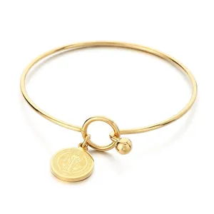 Elegant gold-tone stainless steel bangle featuring a Saint Benedict religious medal charm