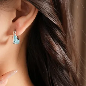 Close-up of a vintage square huggie earring featuring light blue pavé zircon stones on model's ear