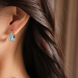 Close-up of vintage silver hoop earring with turquoise zircons on model
