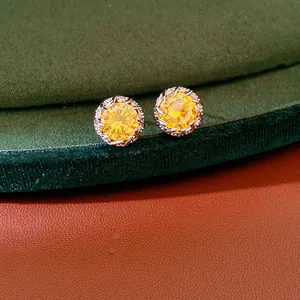 Detailed macro shot of elegant round yellow zircon stud earrings on luxury green velvet