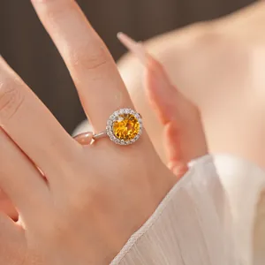 Close-up of elegant round yellow zircon ring with halo setting on a model finger.