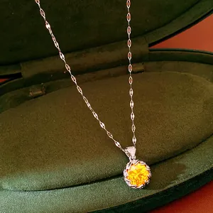 Detailed view of a luxury silver necklace with a large round yellow zircon pendant