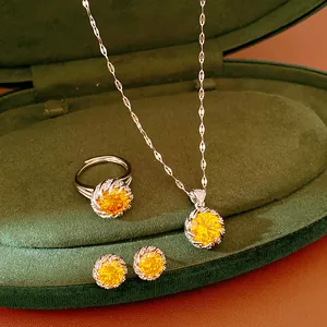 Elegant jewelry set with yellow zircon necklace, ring, and earrings on green velvet box.