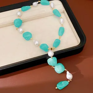 Detail view of irregular teal acrylic and white pearl necklace on a jewelry tray.