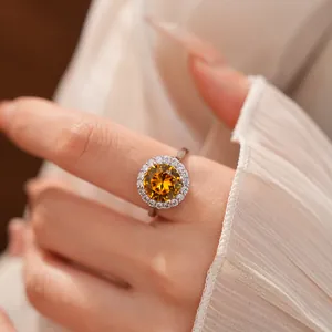 Close-up of an elegant silver ring featuring a vibrant yellow round zircon in a halo setting
