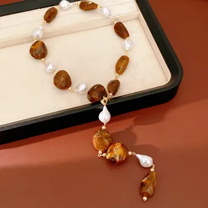 Detail view of irregular brown acrylic and white pearl necklace on jewelry tray
