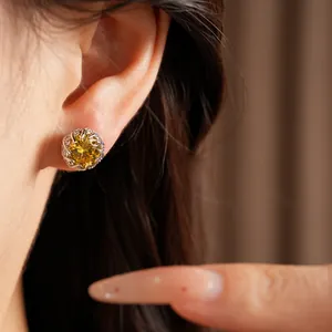 Close-up view of a silver stud earring with a brilliant round yellow zircon stone
