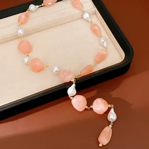 Detail view of irregular peach acrylic beads and baroque pearls on a gold-tone necklace chain