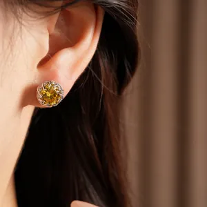 Detailed view of an elegant yellow zircon round stud earring worn on a female model ear
