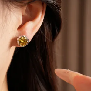 Macro view of a circular silver stud earring with a brilliant yellow zircon stone
