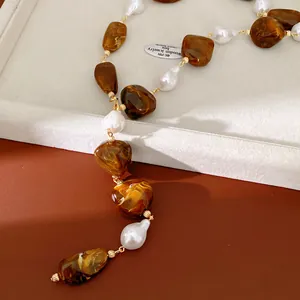 Close-up detail of irregular brown acrylic beads and white pearls on luxury necklace
