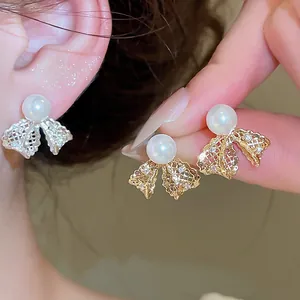 Macro view of intricate 18K gold plated lace bow pearl stud earrings for elegant women