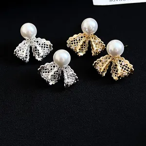 Detailed view of gold and silver lace bow stud earrings with pearls and zircons.