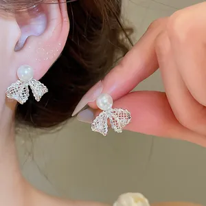 Close-up detail of silver lace bow earrings with elegant white pearl and zircon accents