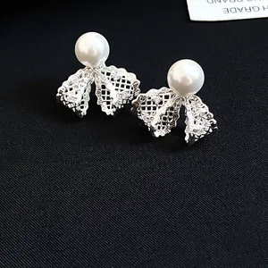 Elegant detail of 18K gold plated lace bow stud earrings with white pearl and zircons
