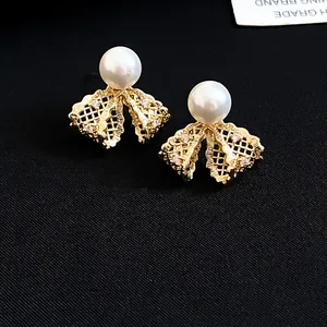Close-up detail of 18K gold plated lace bow pearl stud earrings with zircon accents.