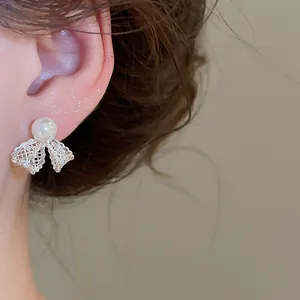 Close-up of an elegant 18K gold plated lace bow earring with a pearl and zircons
