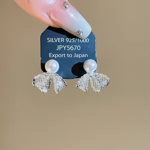 Detailed macro shot of French style lace bow earrings featuring white pearls and zircons