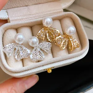 Macro view of elegant 18K gold plated lace bowknot earrings with pearls and zircons.