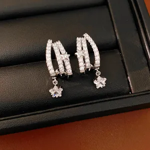 Primo piano di eleganti orecchini a lobo a tre strati con stelle e zirconi luminosi.
