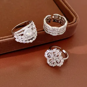 Detailed view of three exquisite silver-tone zircon encrusted open rings on a brown tray.