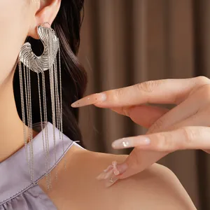 Statement silver irregular C-shaped earring with long bead chain tassels on model
