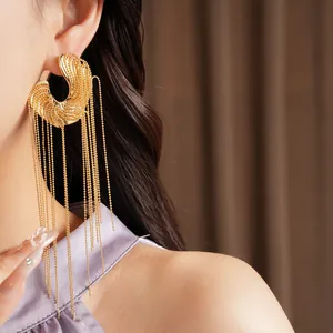 Close-up detail of textured gold C-shaped earring featuring long bead chain tassels.